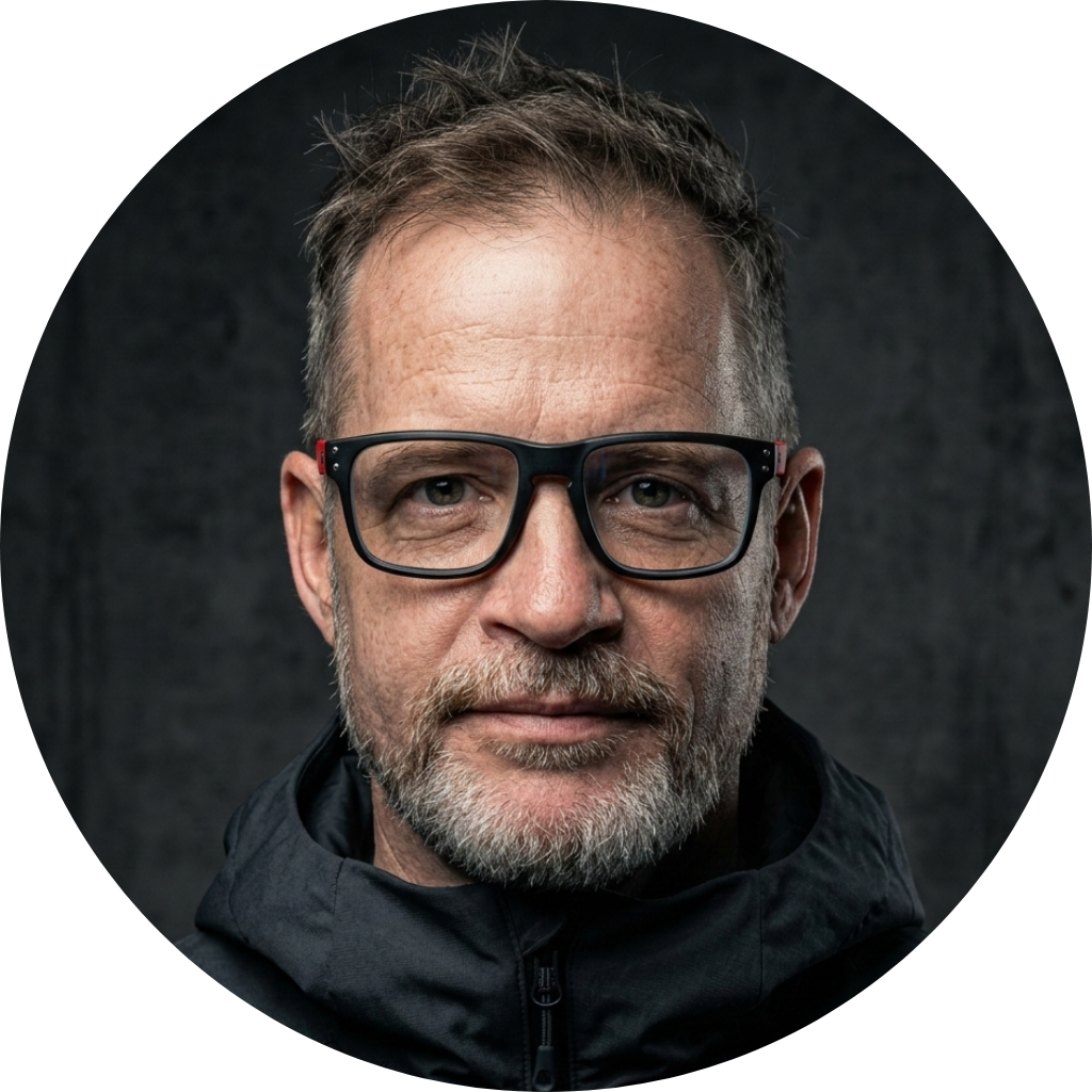 Fekete András biztonsági szakértő portréja szemüvegben, sötét tónusú háttér előtt.